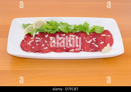 Bresaola avec rocket fromage, salade verte et citron sur table en bois Banque D'Images