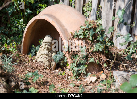 Gnome à dormir dans un endroit isolé et envahi par une partie d'un jardin Banque D'Images