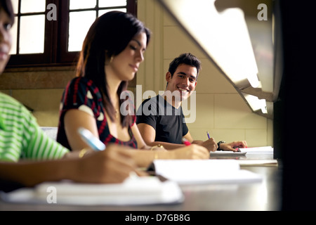 Happy student étudier et écrire, portrait of Hispanic young man doing Homework in college library and smiling at camera Banque D'Images