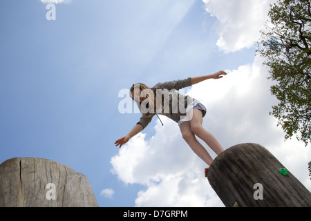 Girl balancing sur tronc d'arbre d'essayer de prendre une grande étape Banque D'Images