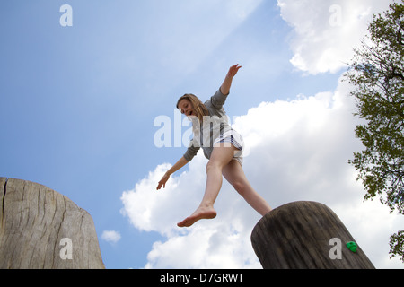 Girl balancing sur tronc d'arbre d'essayer de prendre une grande étape Banque D'Images