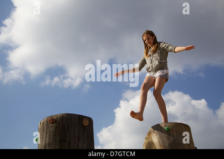 Girl balancing sur tronc d'arbre d'essayer de prendre une grande étape Banque D'Images