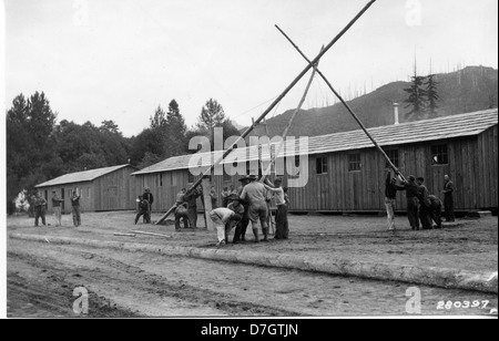 Cette photographie montre des membres du Civilian conservation corps (CCC) levant un mât de drapeau au camp 34 sur le fleuve Cispus. L'image illustre le travail du CCC pendant la Grande dépression, axé sur les travaux publics et les efforts de conservation. Banque D'Images