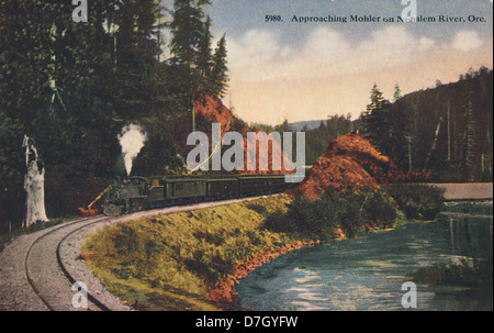 Cette photographie historique capture un train approchant Mohler sur la rivière Nahalem en Oregon, montrant l’importance des chemins de fer dans le développement de la région au cours du XXe siècle. Banque D'Images