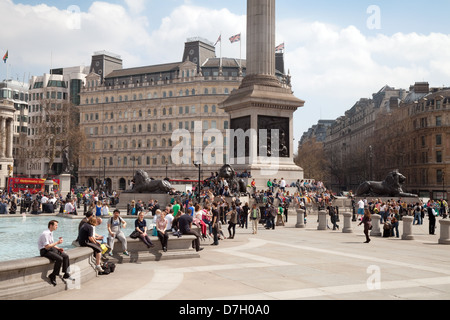 Les gens assis autour de la fontaine, un jour ensoleillé, Trafalgar Square, Central London WC2, UK Banque D'Images