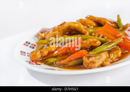 Faire sauter les lanières de poulet frit avec les haricots verts, le poivron et les carottes en sauce aigre-douce. La délicatesse de l'Asie. Banque D'Images