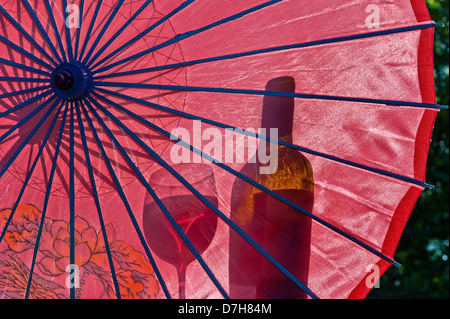 Parasol de jardin avec verre de vin rouge et une bouteille en silhouette Banque D'Images