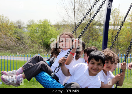 Enfants jouant sur un pneu / balançoire pneu dans une aire de Londres. Banque D'Images