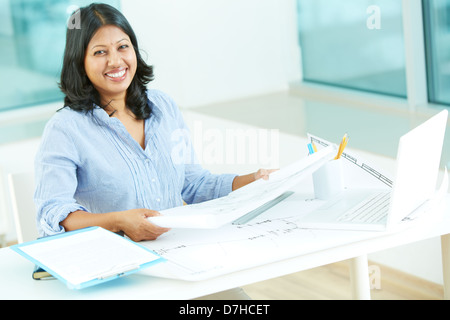 Portrait of happy young businesswoman with croquis de construction looking at camera in office Banque D'Images