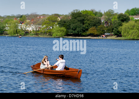 Un couple prenez un bateau à rames sur le lac dans Roath Park, Cardiff, Royaume-Uni. Banque D'Images