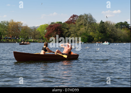 Un couple prenez un bateau à rames sur le lac dans Roath Park, Cardiff, Royaume-Uni. Banque D'Images