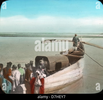 Cette image représente un ferry traversant l'Euphrate près de Tellel-Abmar. La photographie, tirée des Archives de l’OSU, met en valeur la vie sur la rivière et l’importance des ferries pour le transport dans la région. L’Euphrate est l’un des plus longs fleuves d’Asie occidentale, jouant un rôle crucial dans la connectivité et le commerce régionaux. Banque D'Images