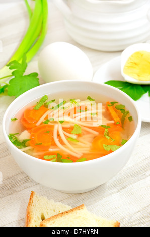 La soupe avec les pâtes et les légumes dans un bol blanc sur une table Banque D'Images