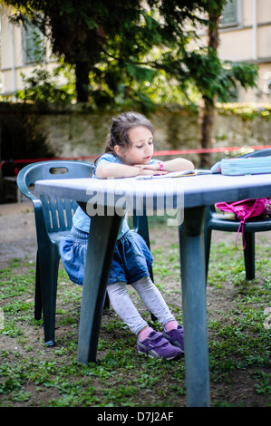 Petite fille se lit sur la table dans le jardin Banque D'Images