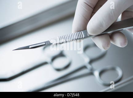 Close up of main dans les gants chirurgicaux dentaires holding scalpel, studio shot Banque D'Images