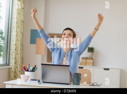 Happy woman in office raising arms up Banque D'Images