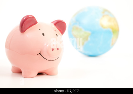 Smiling pink piggy bank avec un globe du monde en arrière-plan. Banque D'Images