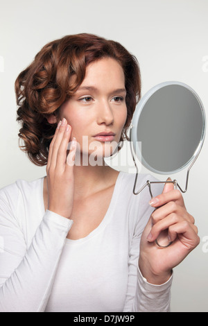 Studio shot portrait de jeune femme regardant elle-même dans le miroir Banque D'Images