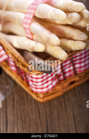 Asperges Blanches attachées avec un ruban de tissu dans un petit panier avec un couteau Banque D'Images