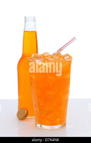 Un verre de soda à l'orange rempli de glace et une paille à boire, avec une bouteille au derrière. Banque D'Images