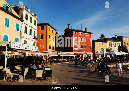 Cafés et restaurants sous les bâtiments de couleur pastel au port de Rovinj, Croatie. Banque D'Images