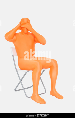 Homme mûr en orange zentai avec mains couvrant les yeux Banque D'Images