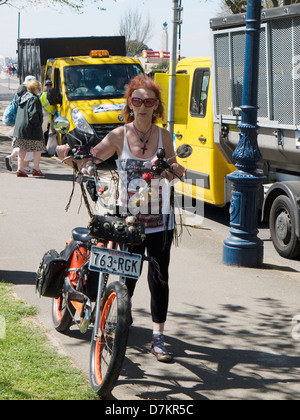 Femme en poussant un vélo personnalisé le long de front Banque D'Images