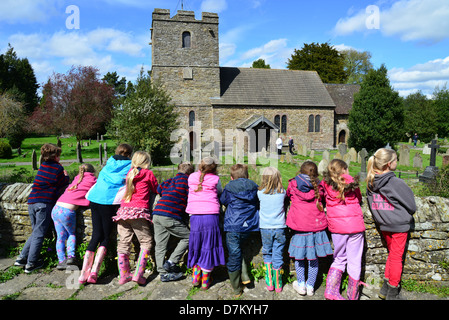 Les enfants se reposer sur le mur de Stokesay Castle, montrant St John the Baptist Church, Stokesay, Shropshire, Angleterre, Royaume-Uni Banque D'Images