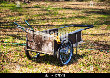 Un panier de jardin et d'outils avec des gants pendaison sur le côté car elle se situe dans un gazon prêt à aller travailler. Banque D'Images