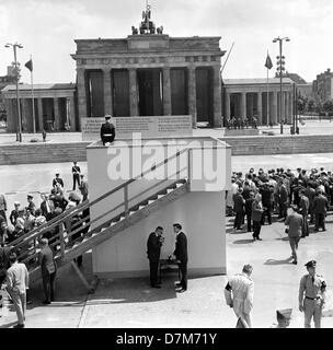 Président américain John F. Kennedy va visiter un point de vue sur le mur de Berlin le 26 juin 1963. Les fonctionnaires de la RDA avait couvert la porte de Brandebourg avec un drapeau rouge et a également installé une affiche traitant directement de la présidente. Banque D'Images