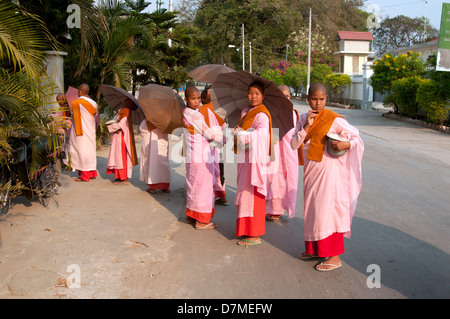 Un groupe de nonnes robe rose recueillir l'aumône en début de soirée dans un village près de lac Inle au Myanmar (Birmanie) Banque D'Images