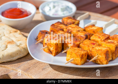 Paneer Tikka Kebab - Tadoori brochettes de fromage indien avec du pain naan, sauce chili, et le concombre et yaourt raita. Eating outdoors Banque D'Images