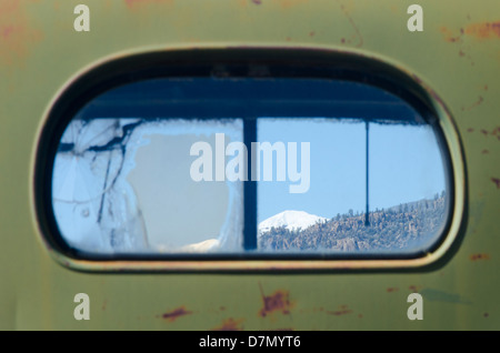 Un vieux camion antique rouille lentement dans une zone de montagne, avec une vue sur les montagnes au-delà. L'accent est mis sur les montagnes. Banque D'Images