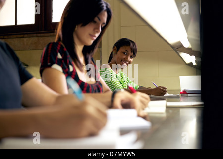 Portrait of happy female student l'écriture et la préparation de l'essai, jolie black girl smiling at camera in college library Banque D'Images
