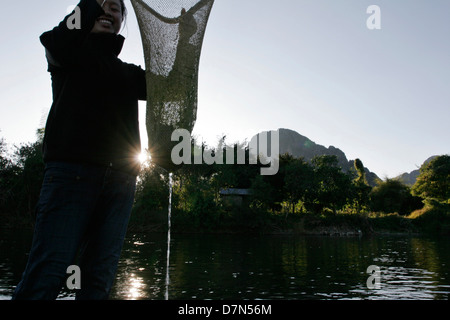 Une jeune fille locale recueille des algues d'eau douce "Kai" de la rivière Nam Song à Vang Vieng. Banque D'Images