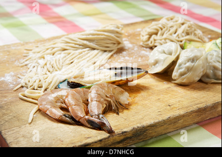 Crevettes, moules, dim sum, et des pâtes sur une planche à découper. Restaurant coréen Banque D'Images