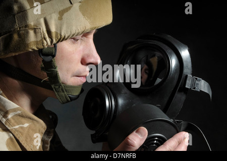 Soldat tenant un respirateur et portant des uniformes de camouflage désert militaire britannique, sur un fond noir. Banque D'Images