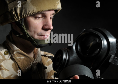 Soldat tenant un respirateur et portant des uniformes de camouflage désert militaire britannique, sur un fond noir. Banque D'Images