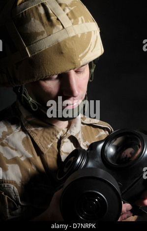 Soldat tenant un respirateur et portant des uniformes de camouflage désert militaire britannique, sur un fond noir. Banque D'Images