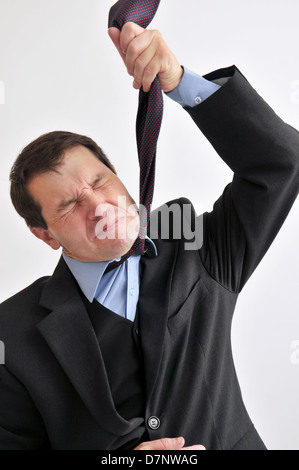 Businessman at wits end comme il l'étouffe avec sa propre cravate. Banque D'Images