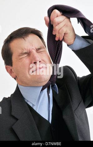 Businessman at wits end comme il l'étouffe avec sa propre cravate. Banque D'Images