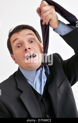 Businessman at wits end comme il l'étouffe avec sa propre cravate. Banque D'Images