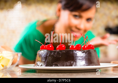 Asian woman présentant des gâteaux au chocolat avec cerises elle cuit dans sa cuisine pour le dessert Banque D'Images