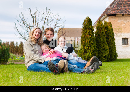 La famille, père, mère et filles, assis ensemble sur un pré, ils rient et s'amuser Banque D'Images
