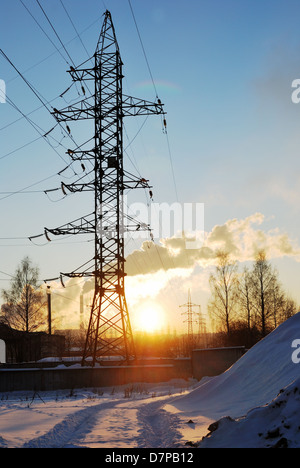 L'hiver, le paysage industriel support power lines at sunset Banque D'Images