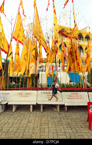 PHUKET, Thaïlande 30 septembre 2011 : Un tout-petit s'exécute sur un banc sous les bannières jaune pour l'assemblée annuelle du Festival Végétarien de Phuket. Banque D'Images