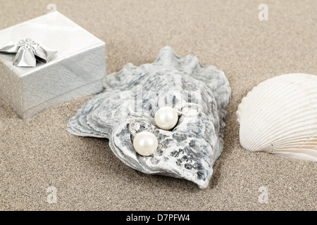 Pearl Earrings et deux obus sur fond de sable Banque D'Images