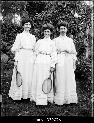 Trois jeunes femmes dans des robes la tenue des raquettes de tennis Banque D'Images