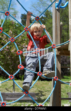 Jeune enfant garçon blond net corde d'escalade en été, aire de jeux Banque D'Images