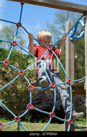 Jeune enfant garçon blond net corde d'escalade en été, aire de jeux Banque D'Images